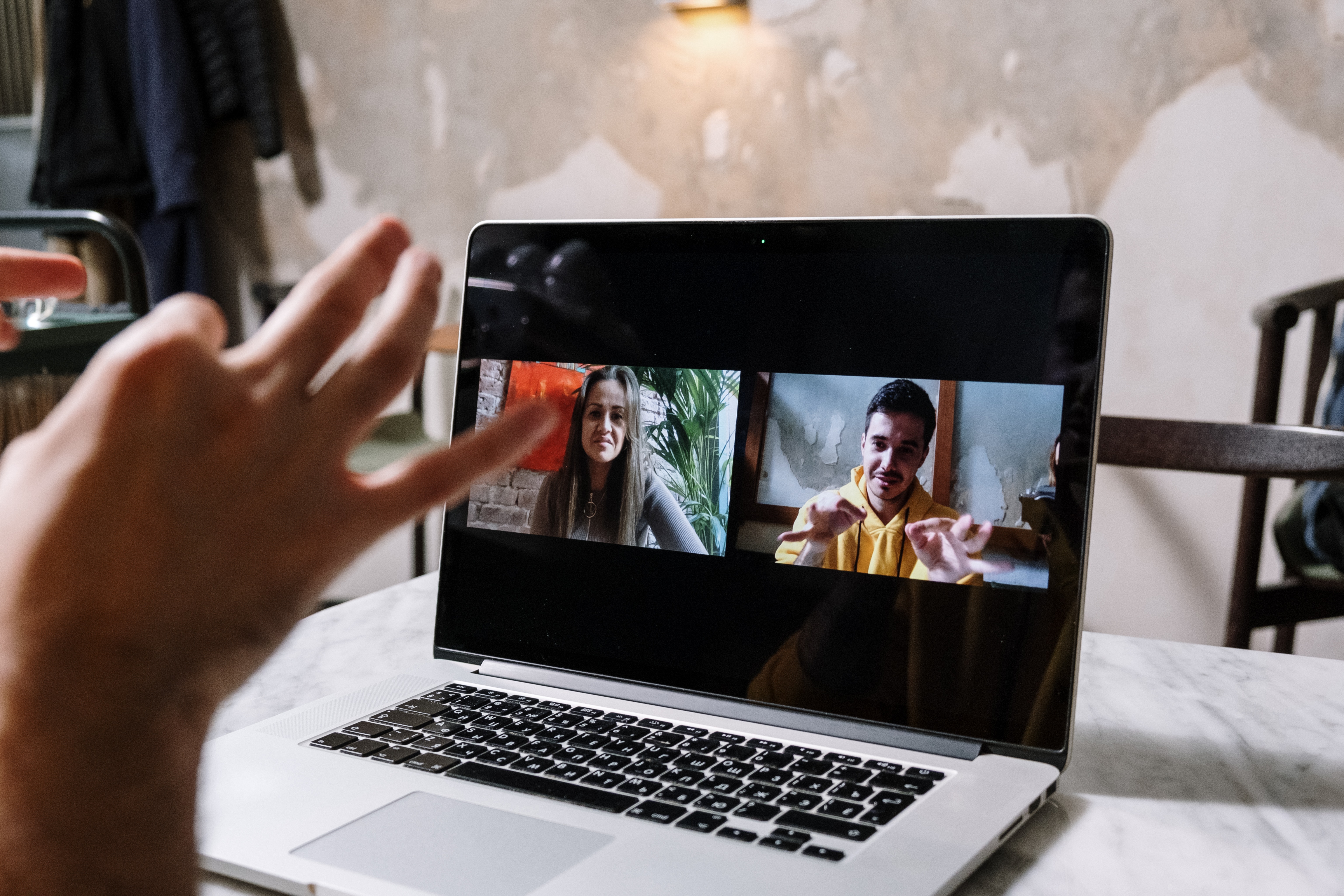 A imagem mostra um homem em uma videochamada com uma menina, eles estão converrsando em libras e a foto foca no notebook, mostrando a conversa. 