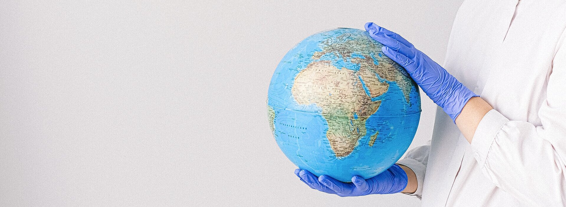 mulher de luvas e máscara segurando um globo do planeta