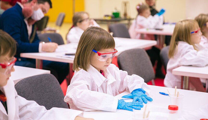 Criança sentada na mesa da sala de aula fazendo experimentos