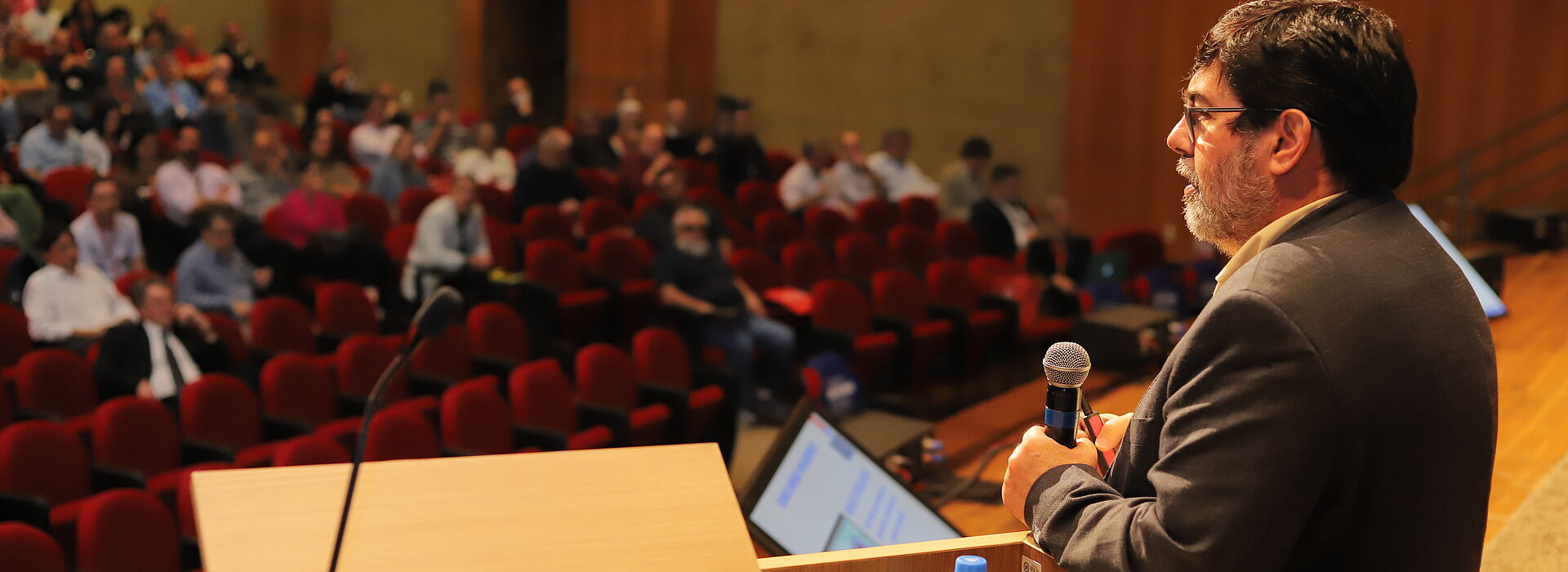 Na imagem, um auditório do Mackenzie com diversas pessoas ao fundo.