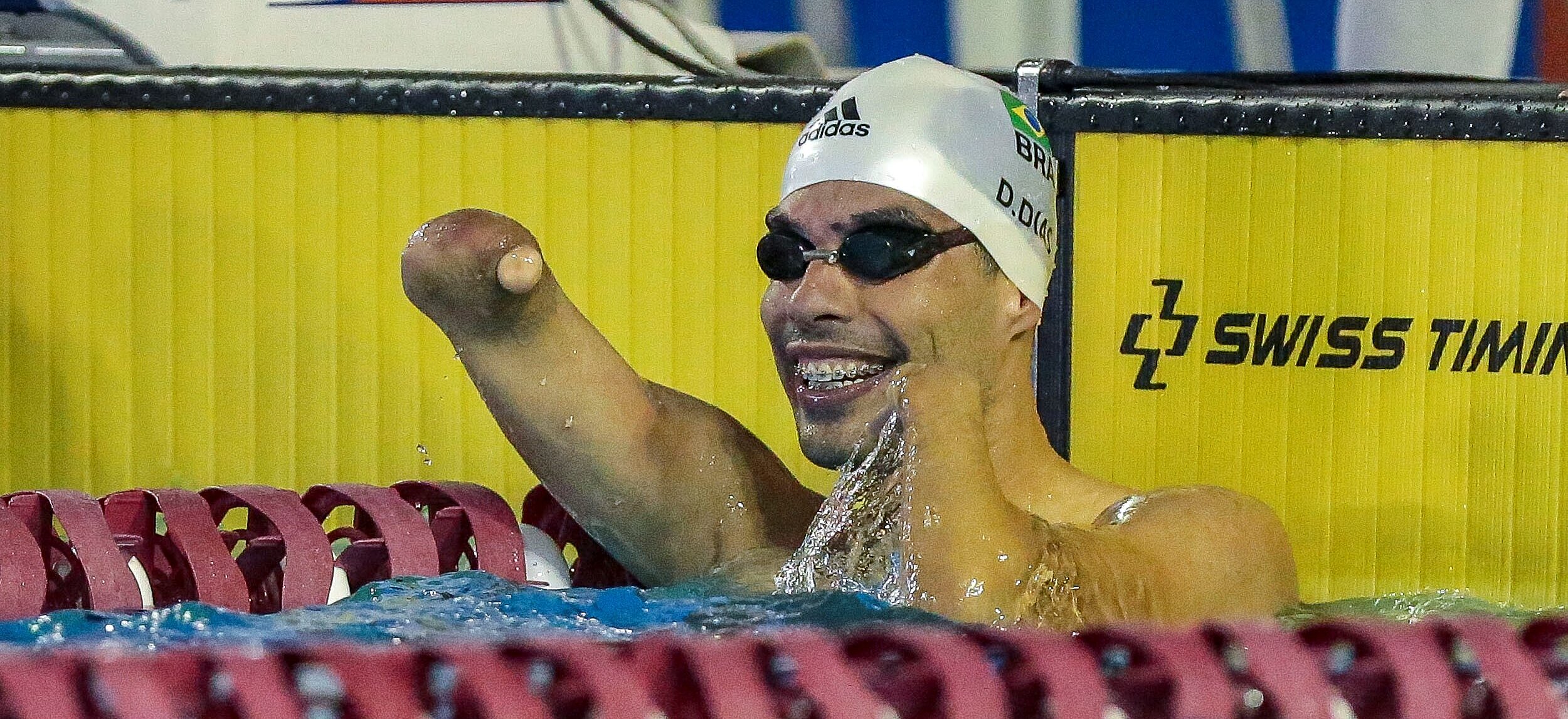 Daniel Dias comemorando o tempo dos 100m livre dentro da água, com óculos e touca de natação.