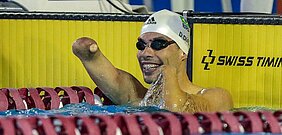 Daniel Dias comemorando o tempo dos 100m livre dentro da água, com óculos e touca de natação.