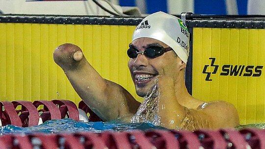 Daniel Dias comemorando o tempo dos 100m livre dentro da água, com óculos e touca de natação.