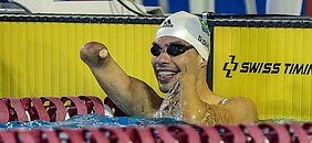 Daniel Dias comemorando o tempo dos 100m livre dentro da água, com óculos e touca de natação.