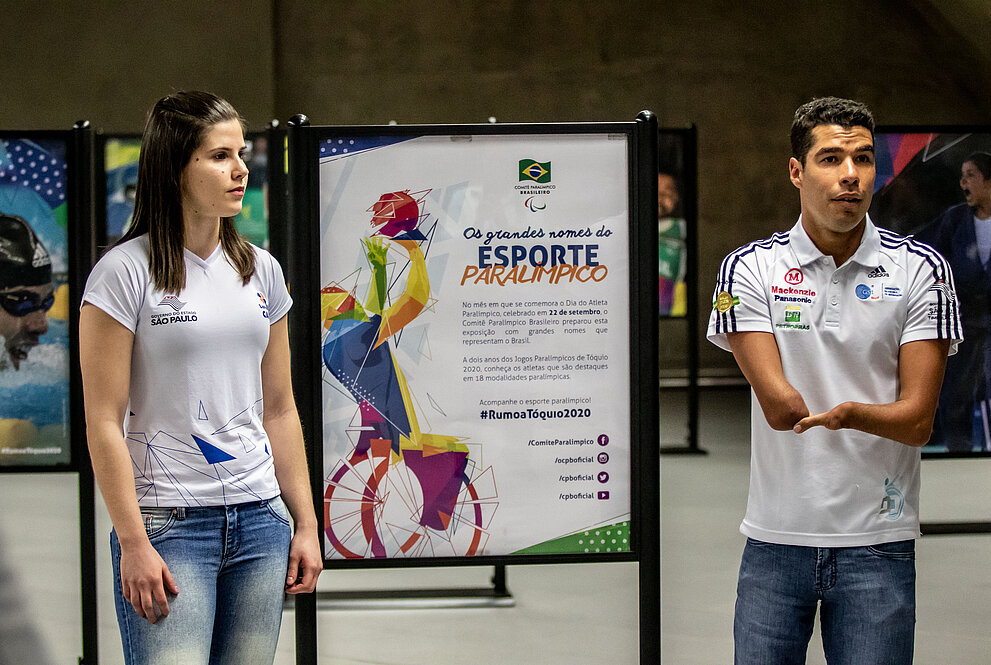 Alana Maldonado e Daniel Dias ao lado das fotos da exposição dos paratletas