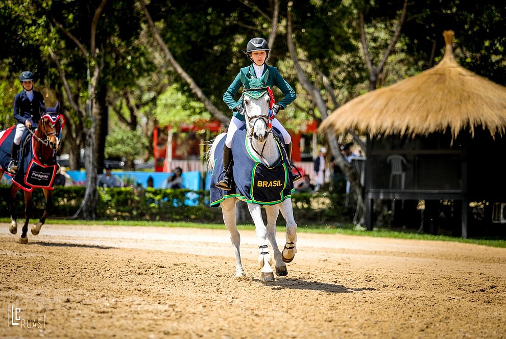 Uma menina montada em um cavalo em competição de saltos com barreiras