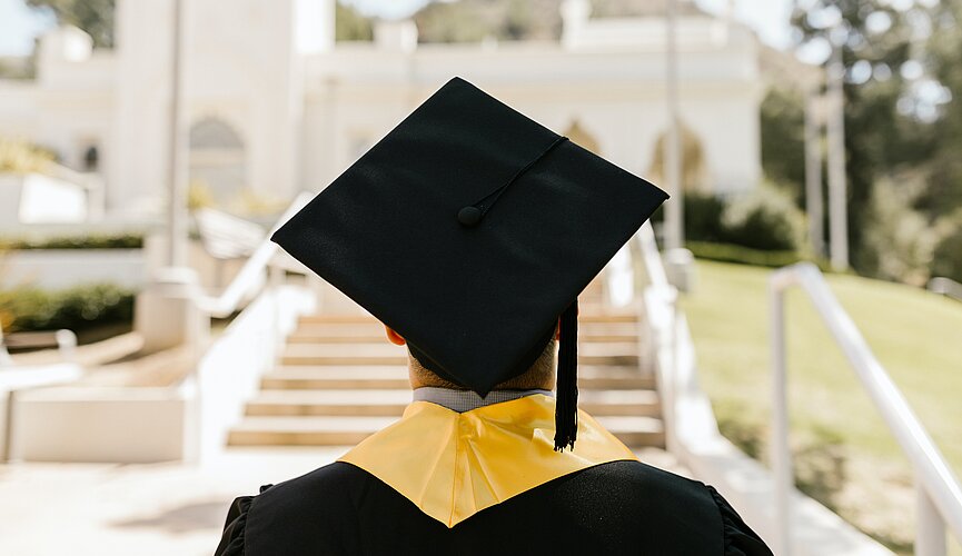 Pessoa de costas com beca e chapéu de formatura 