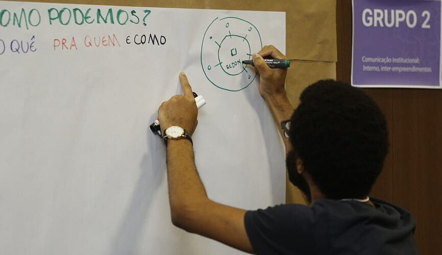 homem escreve em cartolina fixada na parede