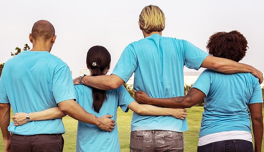 quatro pessoas de costas abraçadas