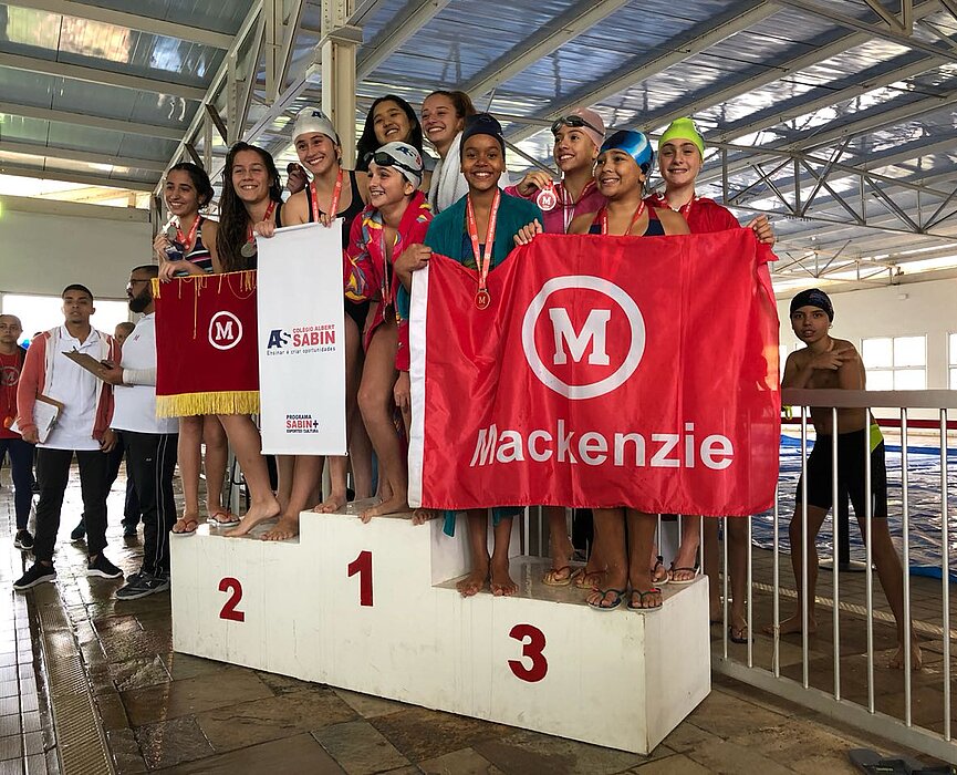 Equipe de natação Mackenzie Brasíliasobre ao pódio.