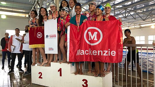 Equipe de natação Mackenzie Brasíliasobre ao pódio.
