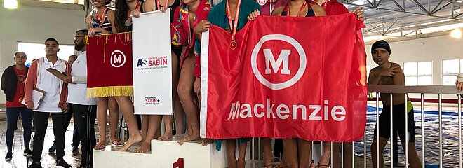 Equipe de natação Mackenzie Brasíliasobre ao pódio.