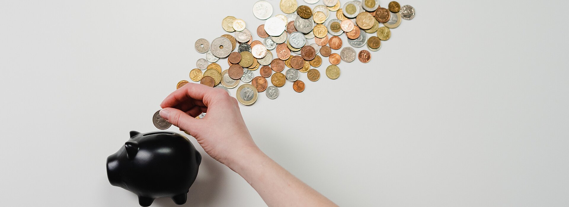 A imagem apresenta um cofre em formato de porco com moedas ao seu redor. 