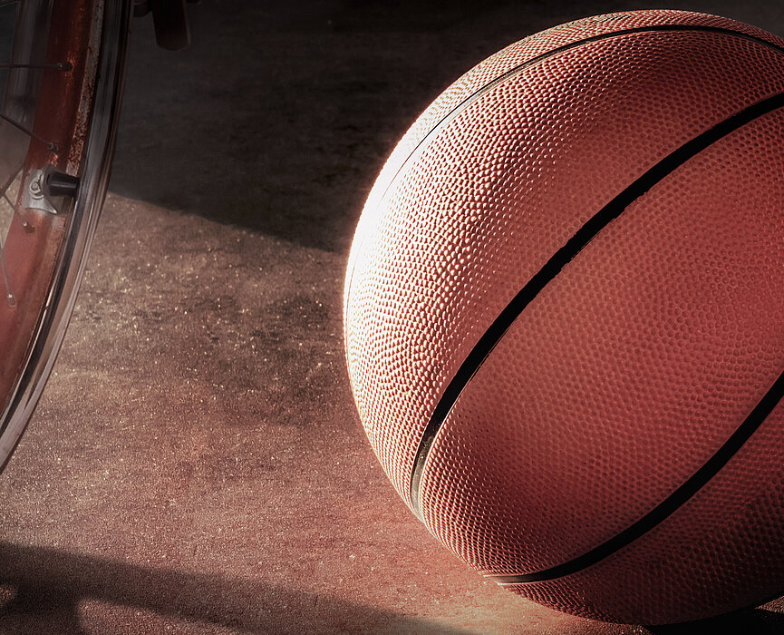 Cadeira de rodas ao lado de bola de basquete.