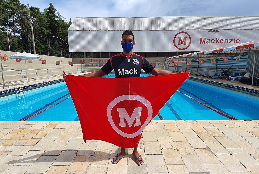 Um homem jovem segurando uma bandeira em frente a uma piscina