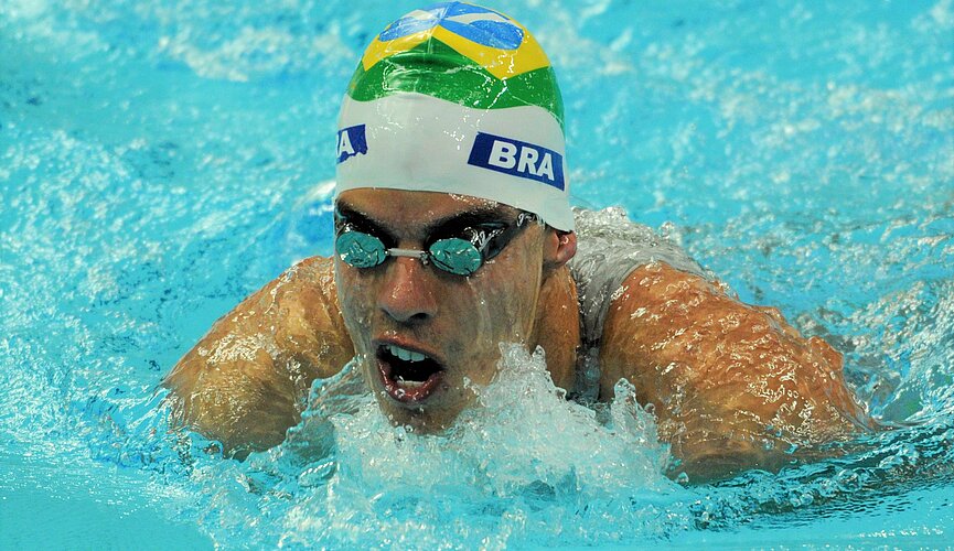 Nadador na piscina competindo com uma touca do Brasil