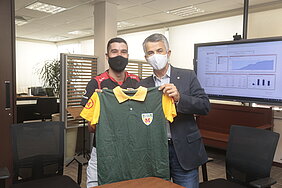 Dois homens em pé segurando uma camisa verde e amarela com um número 10