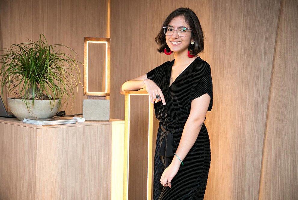 Uma jovem mulher ao lado de uma luminária em formato retangular