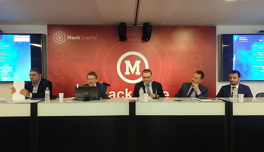 grupo pessoas sentadas, uma do lado da outra 