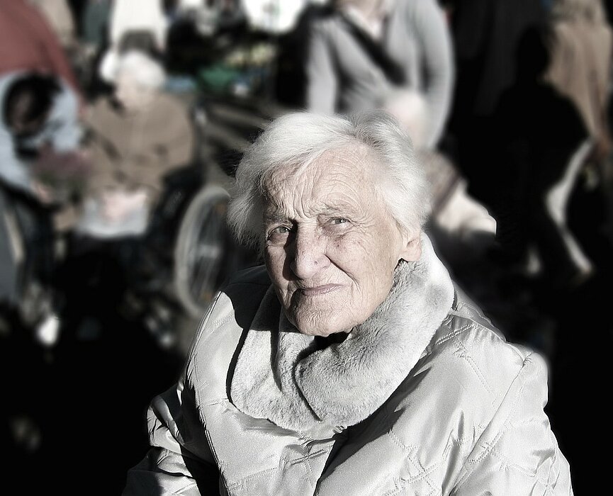 Na foto, mostra uma senhora olhando para a câmera