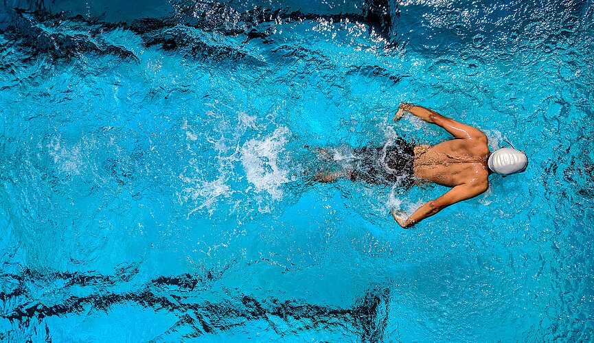 Imagem com um nadador dentro de uma piscina
