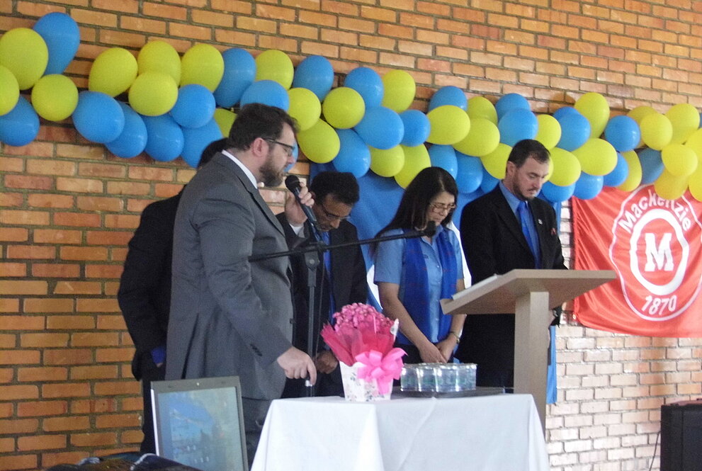 o reverendo está com um microfone na mão ao lado de algumas pessoas realizando a oração no culto do instituto castro