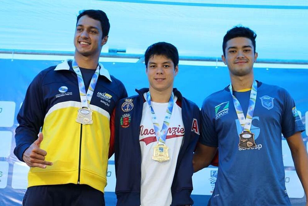 Três homens sorrindo para a foto com medalhas nas mãos