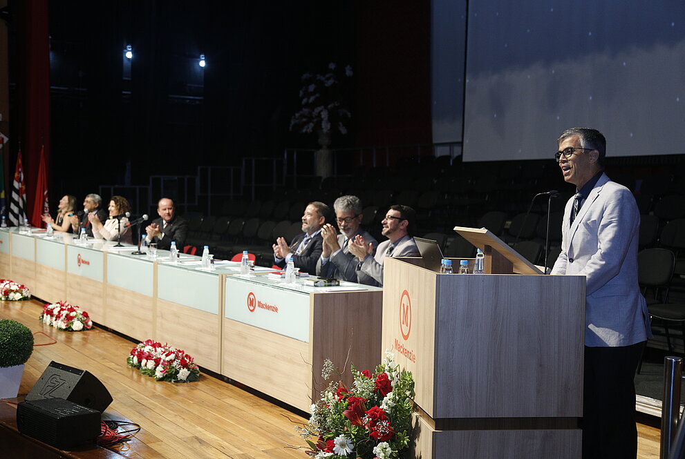 Presidente do IPM discursa ao púlpito com mesa de autoridades em segundo plano.