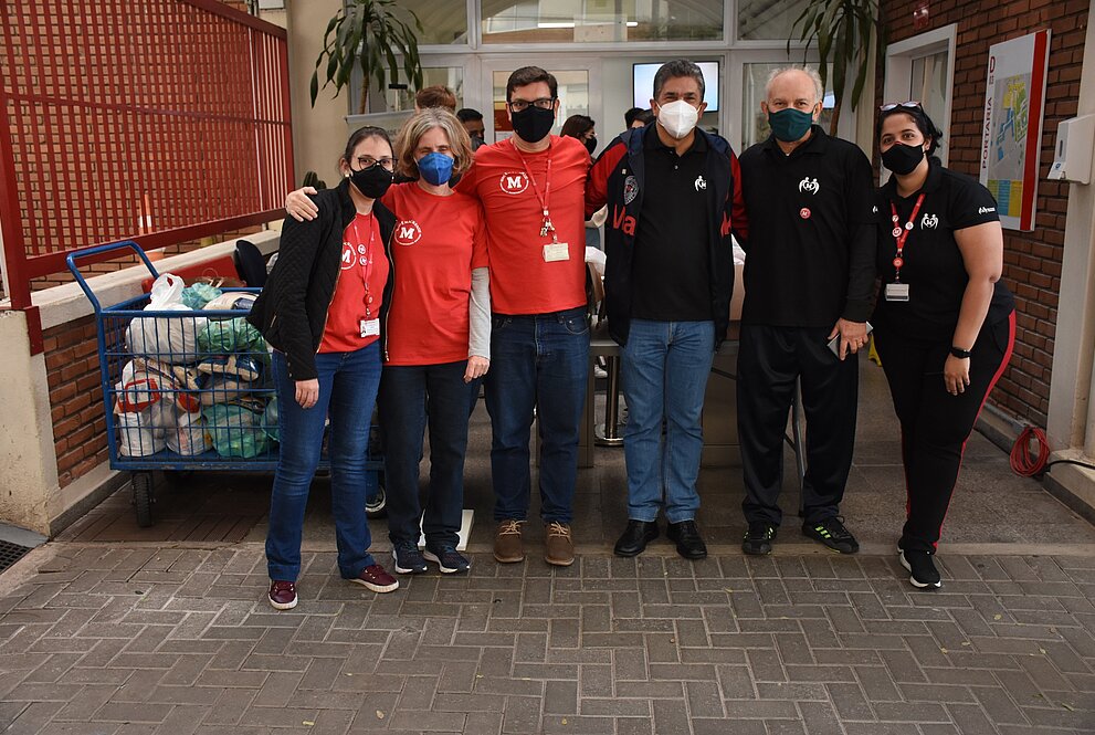 Seis pessoas de máscara posam para foto em frente a entrada do campus Higienópolis do Mackenzie