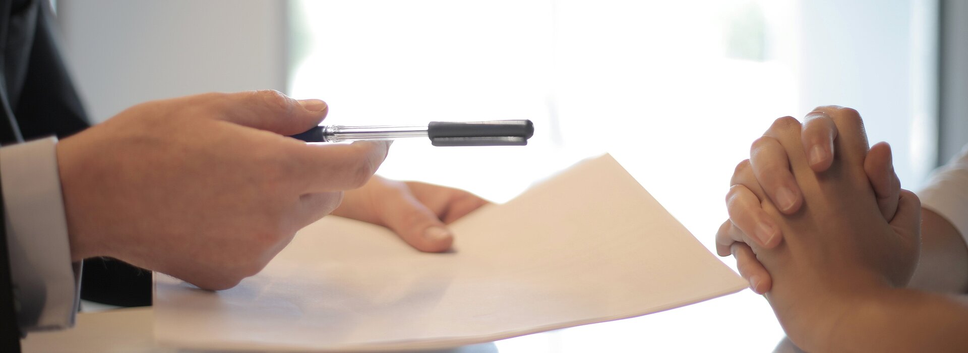 A imagem apresenta uma pessoa prestes a assinar um contrato de emprego. 