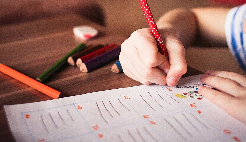 menina desenhando em papel com lápis coloridos