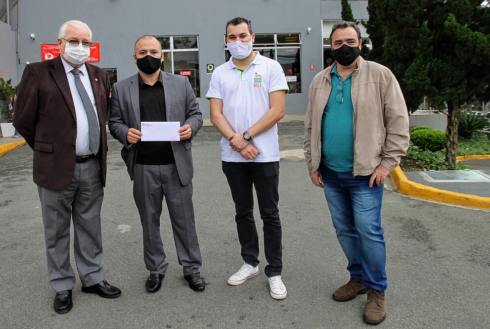 Quatro homens, de pé, posam para foto em frente ao Hospital