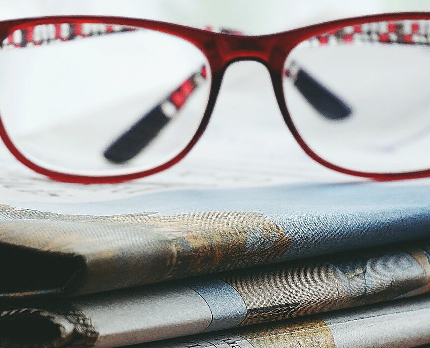 óculos em cima de vários jornais 