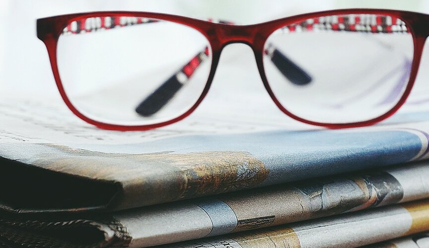 óculos em cima de vários jornais 