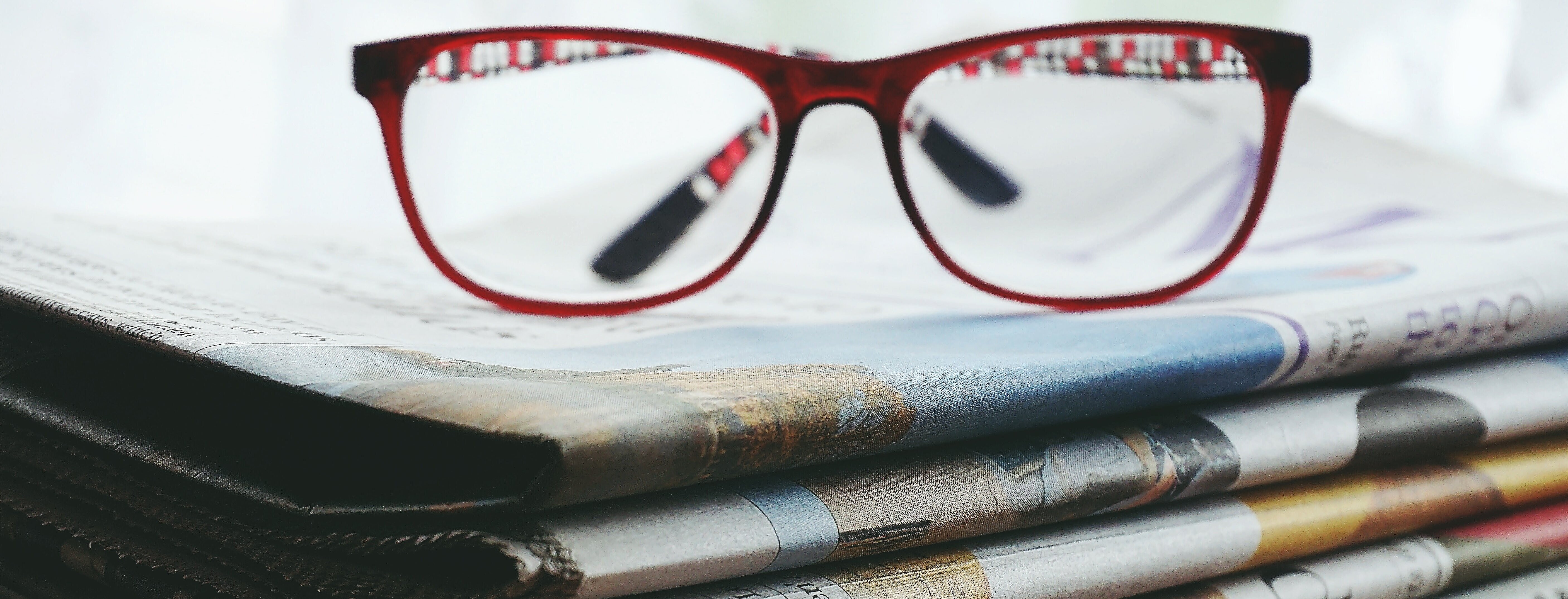 óculos em cima de vários jornais 