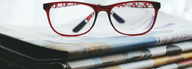 óculos em cima de vários jornais 
