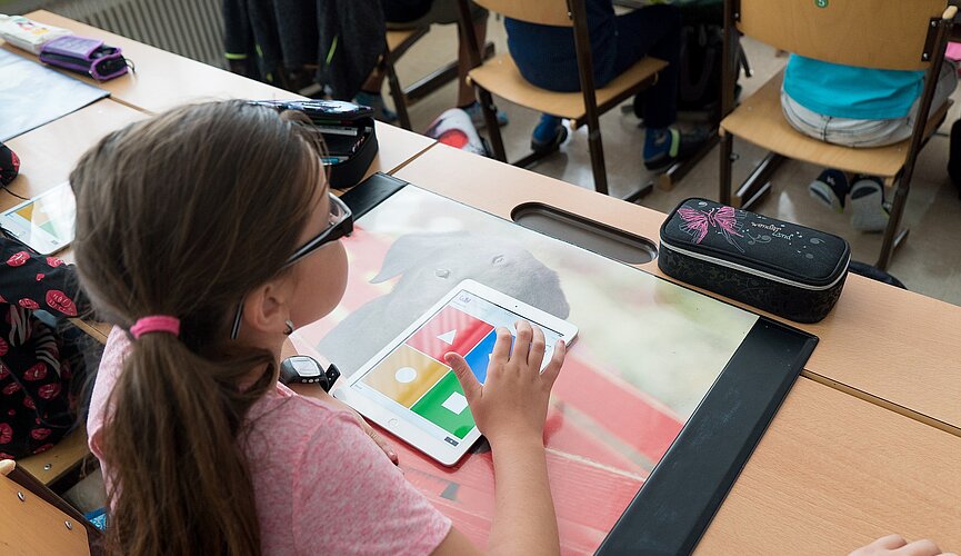 Garota com um tablet fazendo atividade em sala de aula