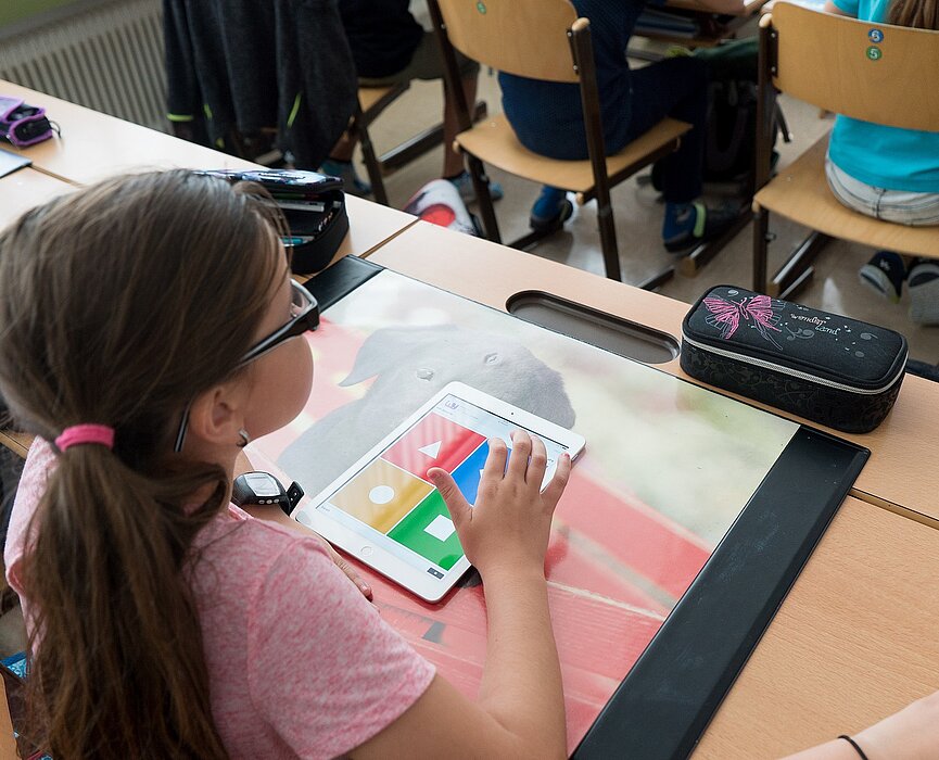 Garota com um tablet fazendo atividade em sala de aula