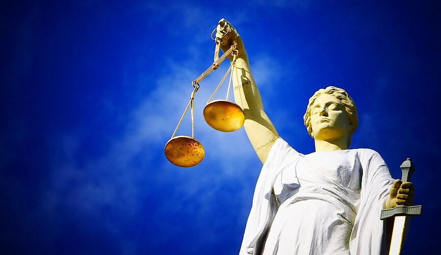 Imagem de uma estátua segurando uma balança, objeto símbolo do julgamento.