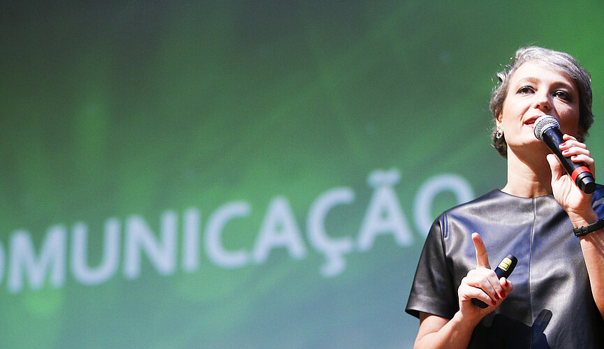 Daniela Cachich no palco com telão ao fundo