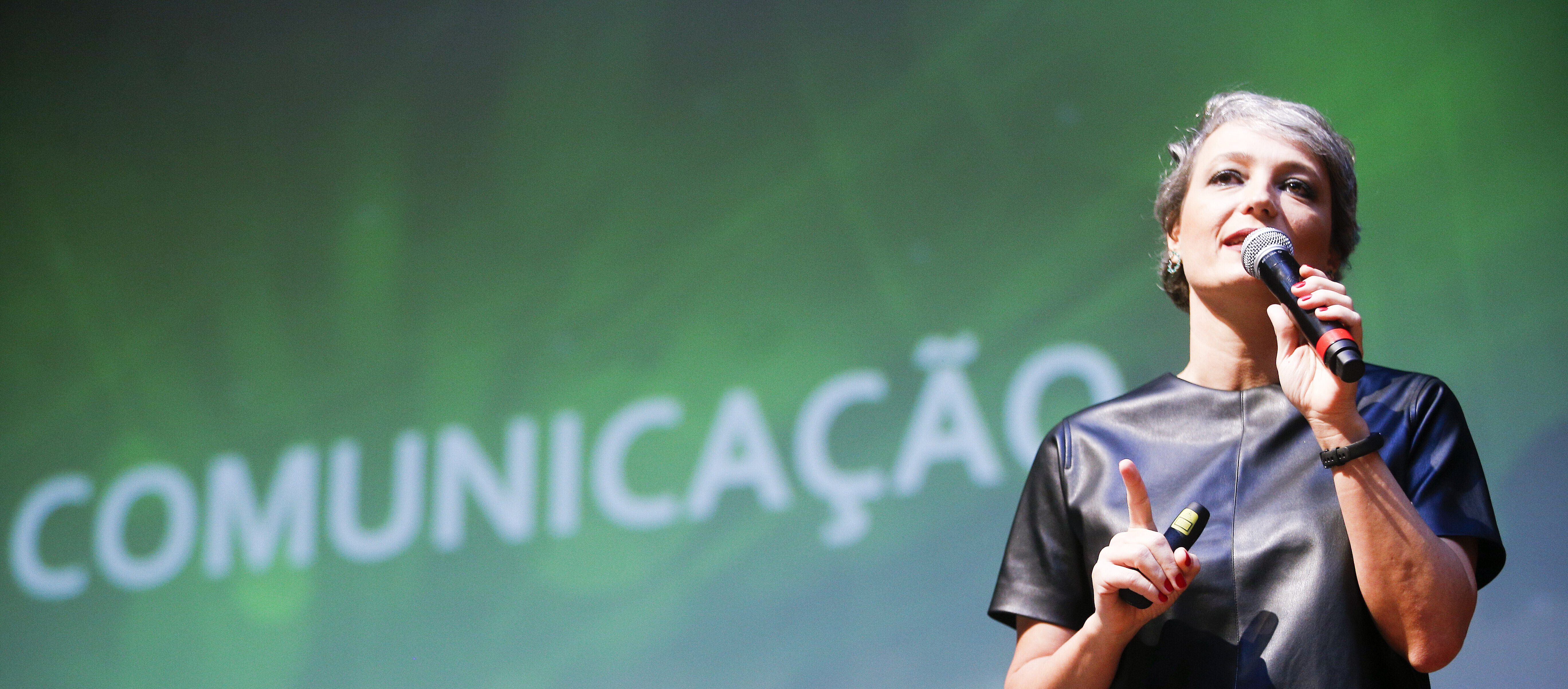 Daniela Cachich no palco com telão ao fundo