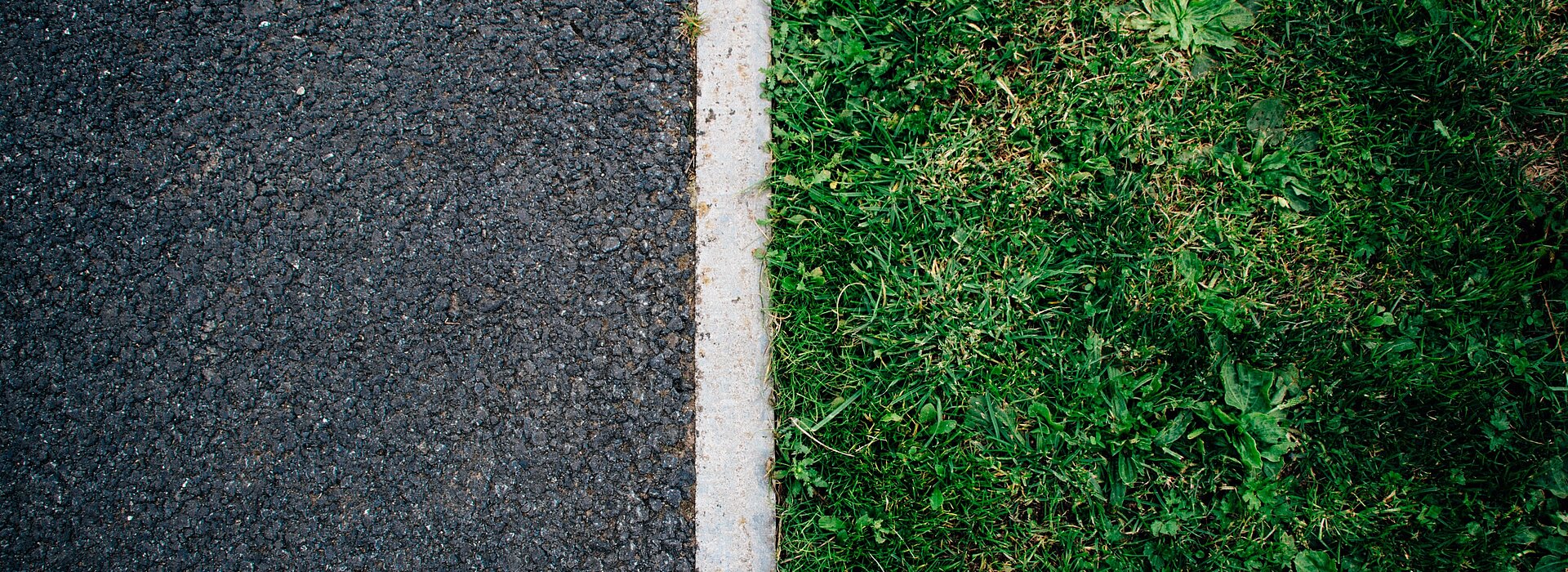 Do lado esquerdo, o asfalto. Do lado direito, a grama. Uma linha branca separa os dois. 