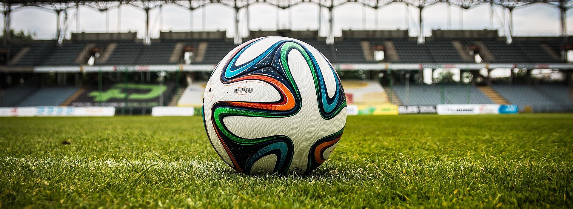 A foto mostra uma bola no meio de campo de futebol