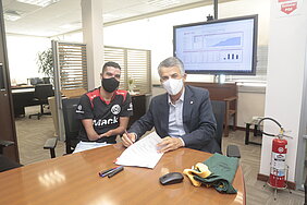 Dois homens sentados assinando um contrato