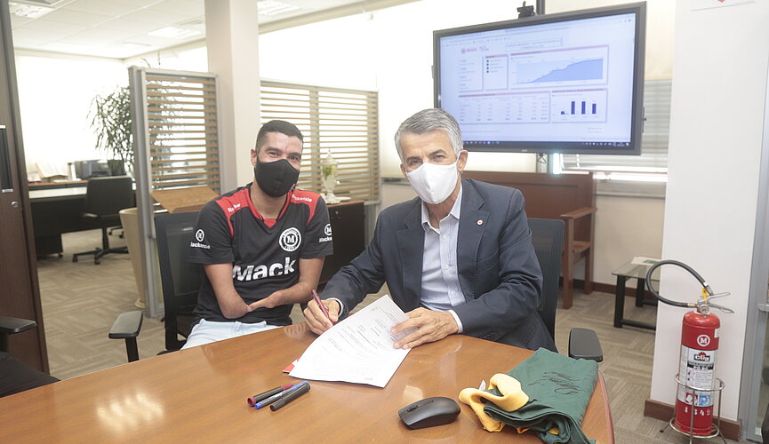 Dois homens sentados assinando um contrato