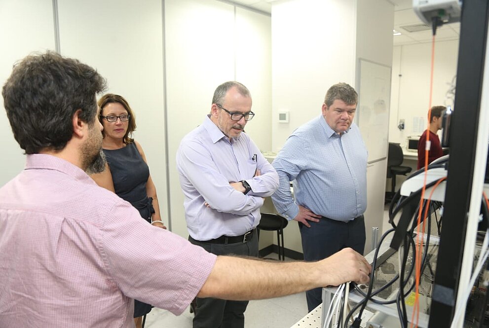 Quatro pessoas observam equipamento eletrônico no laboratório do Mackenzie