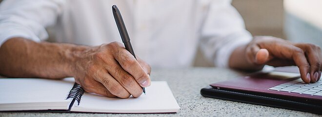 Imagem com um homem escrevendo em uma folha