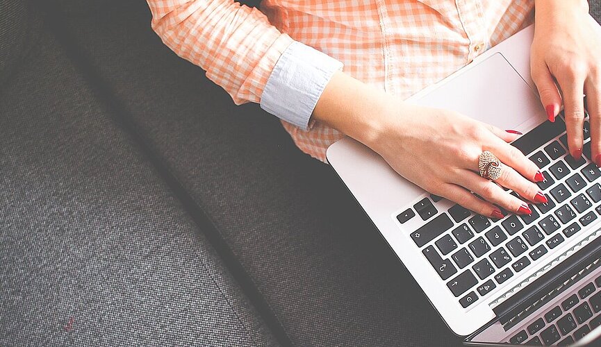 aluna sentada no sofá com laptop no colo