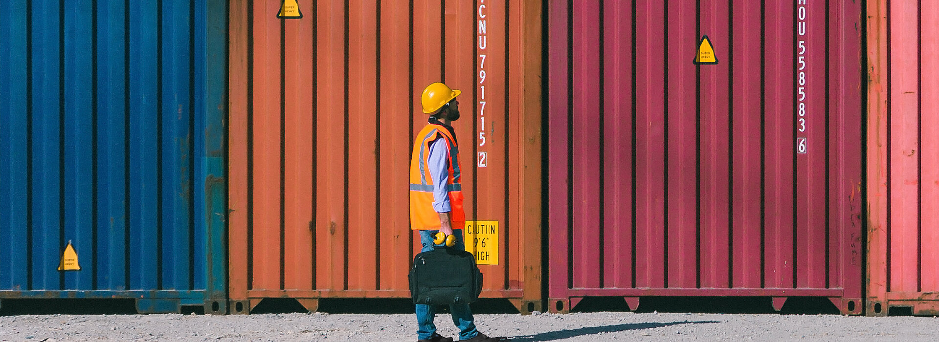 Homem andando e olhando para grandes caixas de suprimento