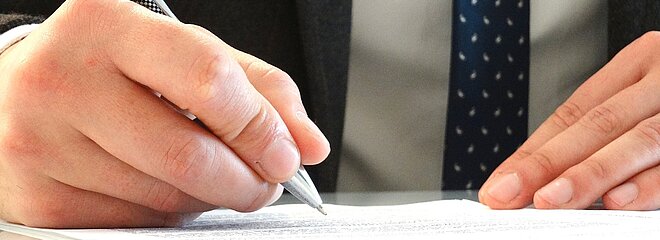 mãos masculinas assinando um documento